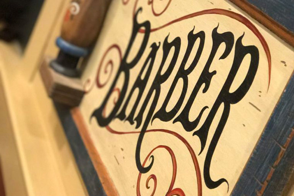 A wooden barbershop sign of an old school Barber